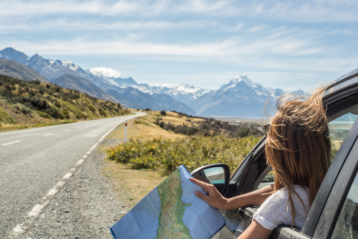 Frau mit Landkarte vor einer Berglandschaft