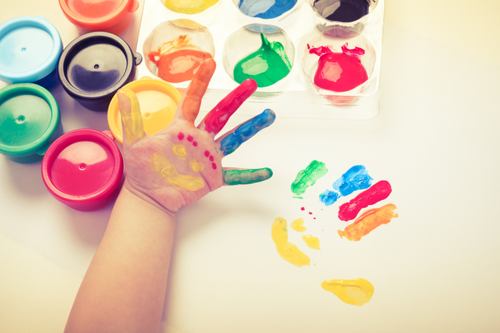 Kinderhand mit Fingerfarben bemalt