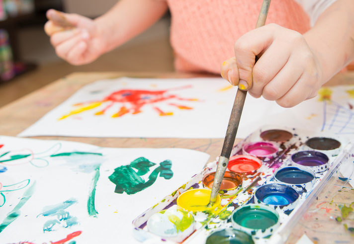 Kind malt mit Wasserfarben ein Bild